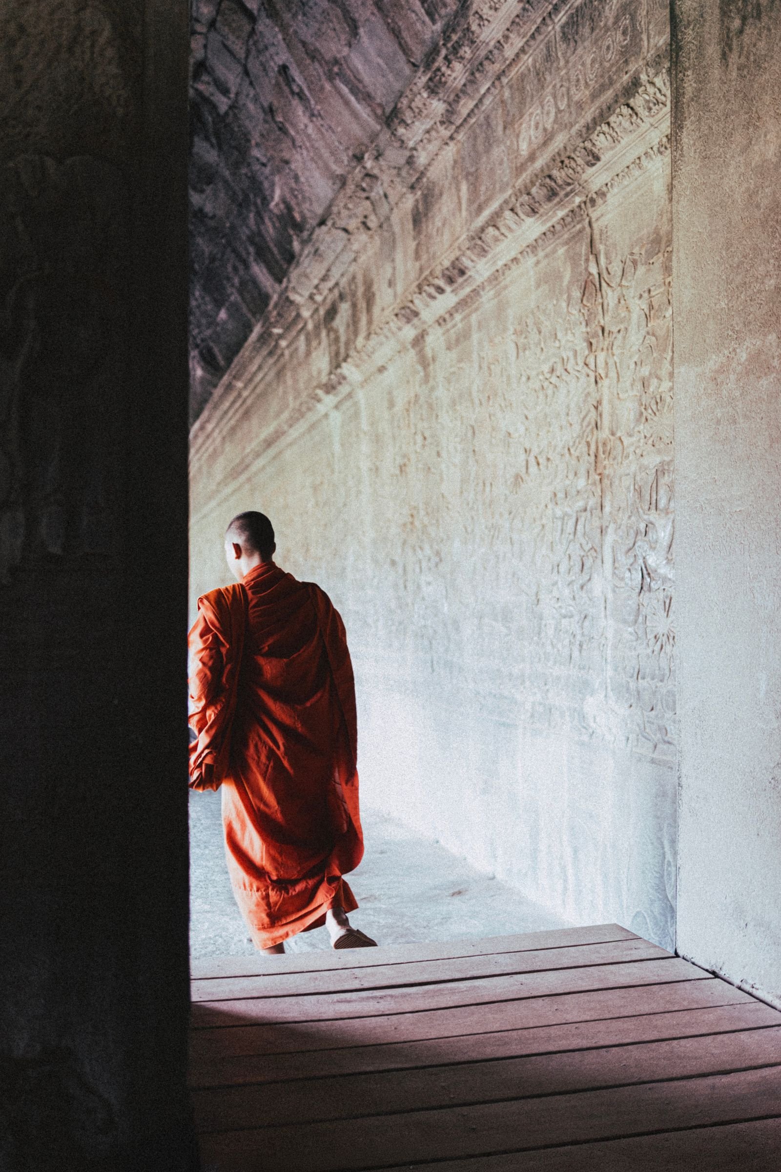 A monk walking through an Angkor Wat corridor